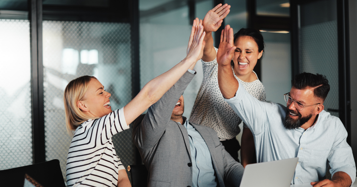 A group of colleagues in an office exchanging a celebratory high five