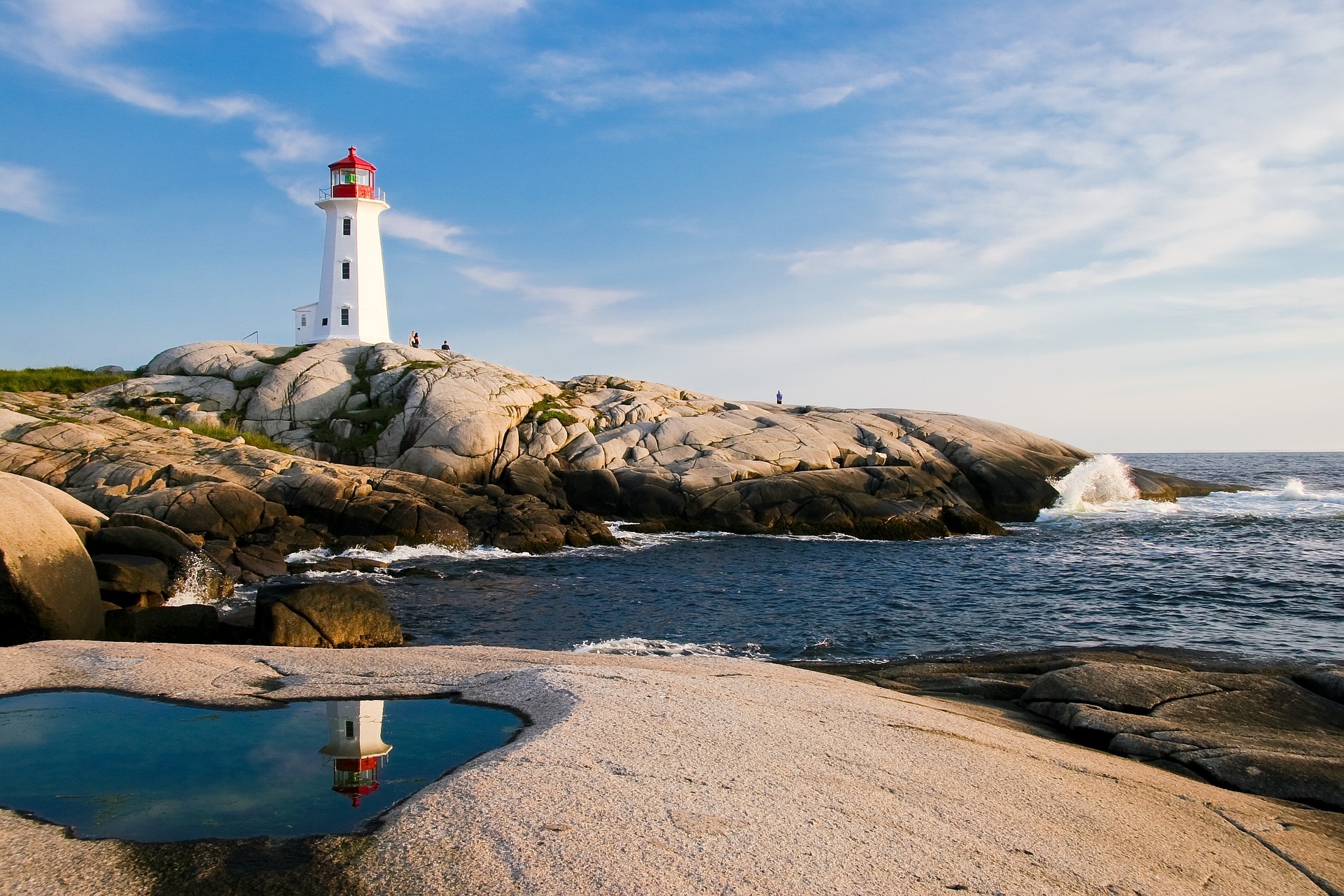 A red and white lighthouse on granite rocks above the sea, the coastal US locations Travel Nursing in the USA assignments are offered in