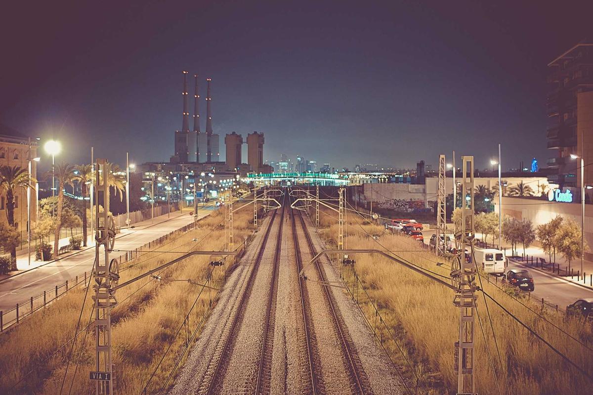 Night railway tracks running toward a lit city skyline - Business Travel Accommodation