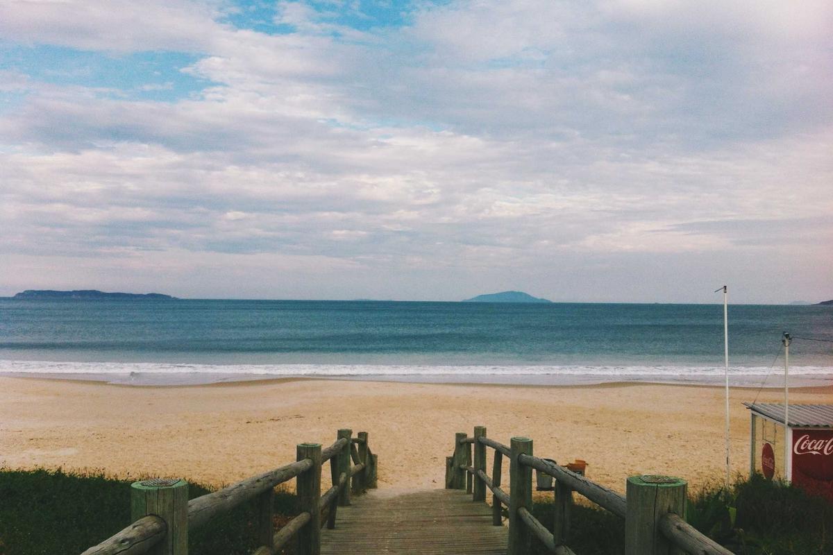 Wooden boardwalk leading to an empty beach and calm sea - Business Travel Accommodation